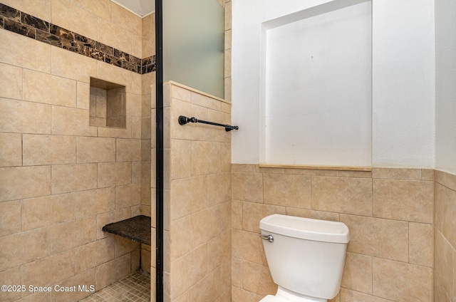 bathroom with a shower with door, tile walls, and toilet