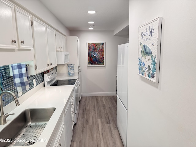 kitchen with white cabinetry, light hardwood / wood-style floors, tasteful backsplash, white appliances, and sink