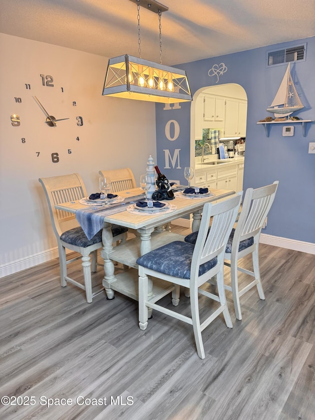 dining space featuring a textured ceiling, light hardwood / wood-style flooring, and sink