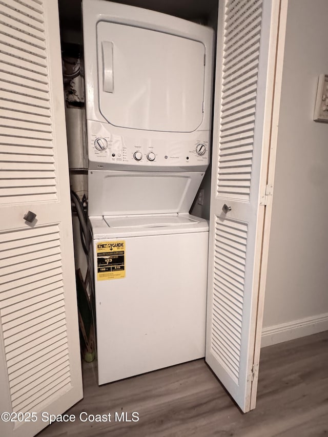 laundry room with wood-type flooring and stacked washer / drying machine