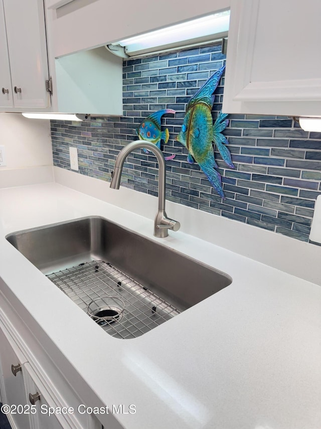 details featuring sink, white cabinets, and tasteful backsplash