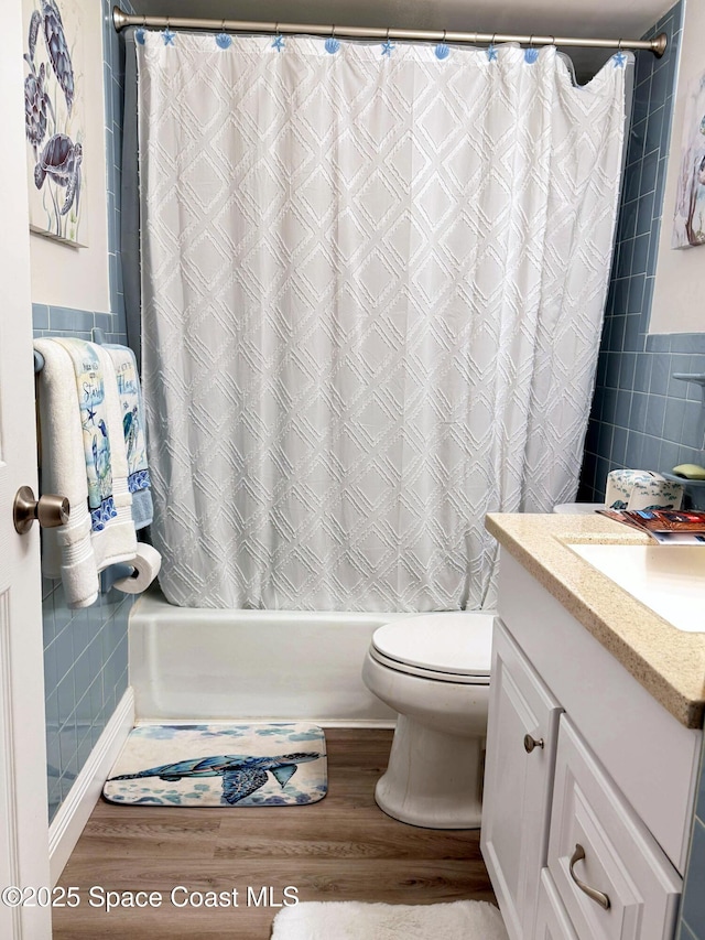 full bathroom with vanity, shower / tub combo, tile walls, toilet, and hardwood / wood-style flooring