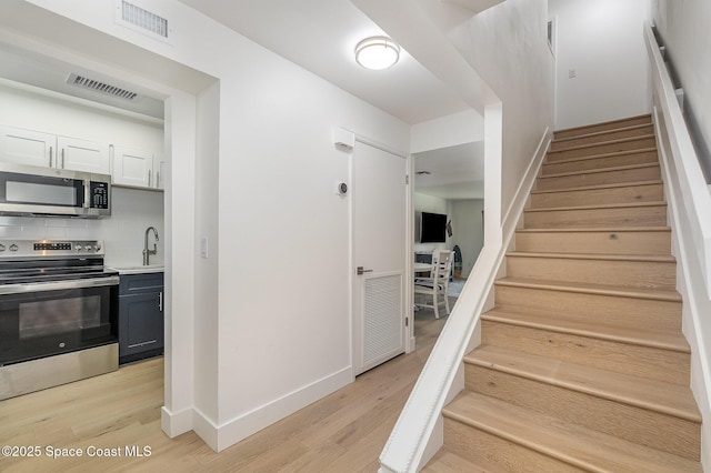 stairway featuring sink and wood-type flooring