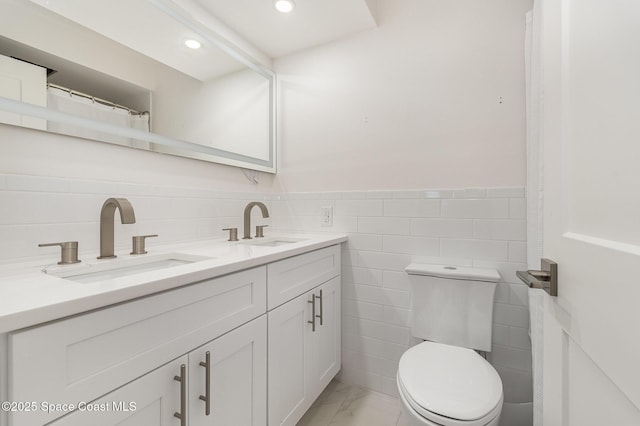 bathroom featuring vanity, tile walls, and toilet