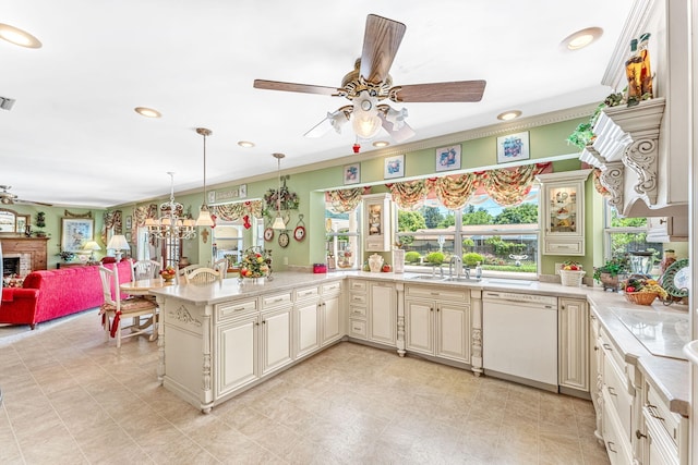 kitchen featuring pendant lighting, dishwasher, a fireplace, cream cabinetry, and kitchen peninsula