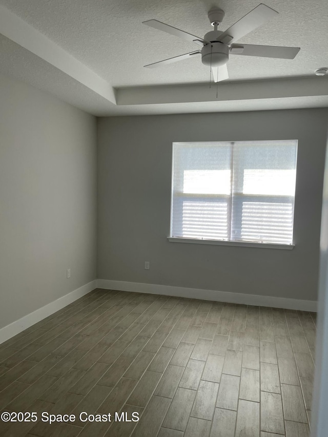 empty room with ceiling fan, wood-type flooring, and a textured ceiling