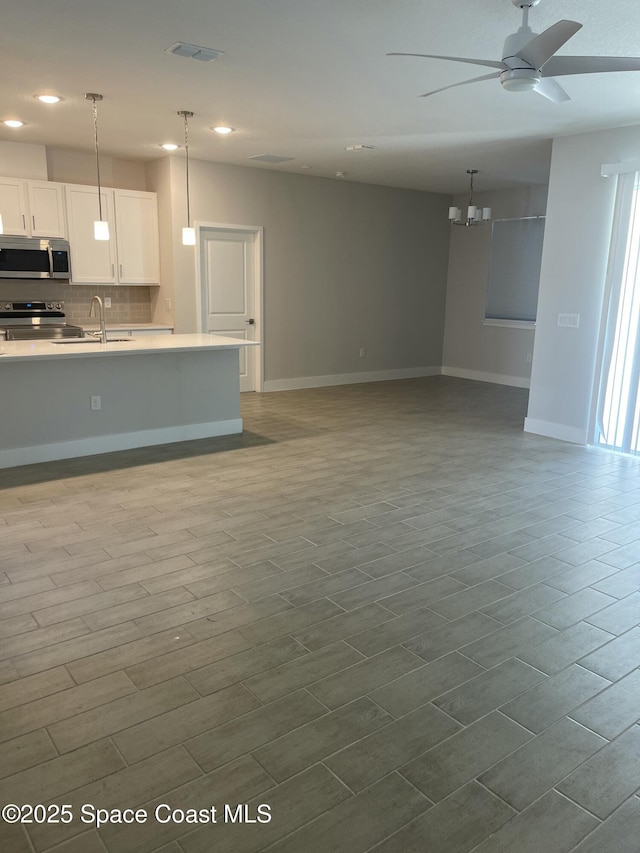 kitchen featuring stainless steel appliances, white cabinetry, pendant lighting, and decorative backsplash