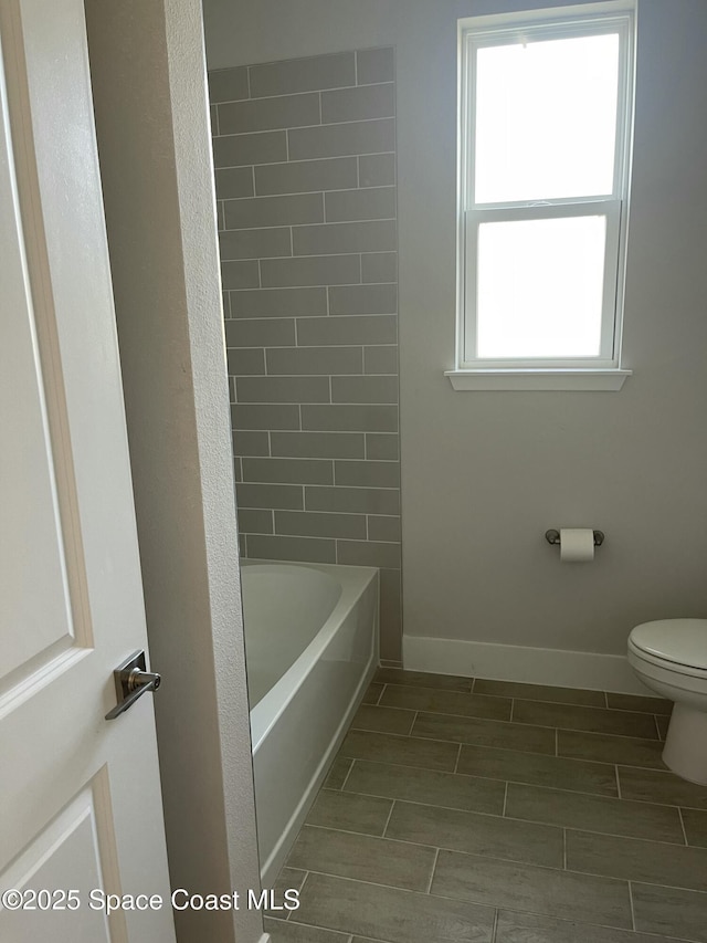 bathroom featuring tiled shower / bath combo and toilet