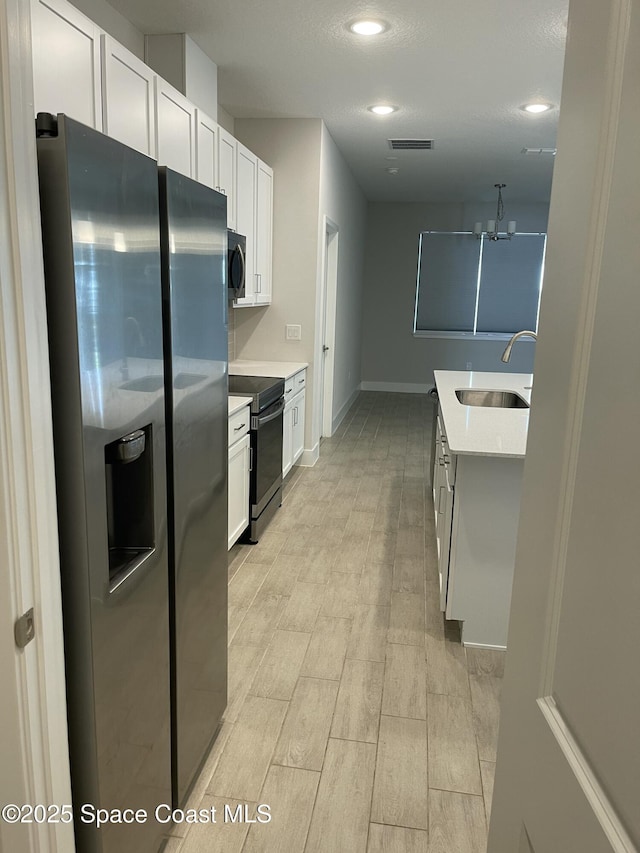 kitchen featuring range with electric cooktop, stainless steel fridge, sink, and white cabinets