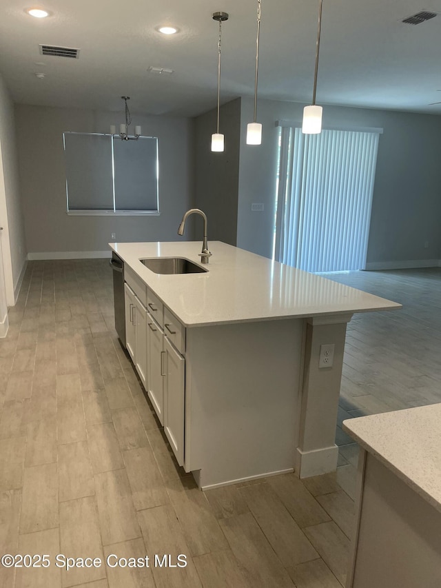 kitchen featuring sink, decorative light fixtures, a center island with sink, dishwasher, and white cabinets