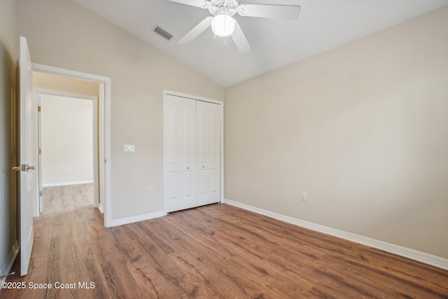 unfurnished bedroom featuring hardwood / wood-style flooring, vaulted ceiling, a closet, and ceiling fan