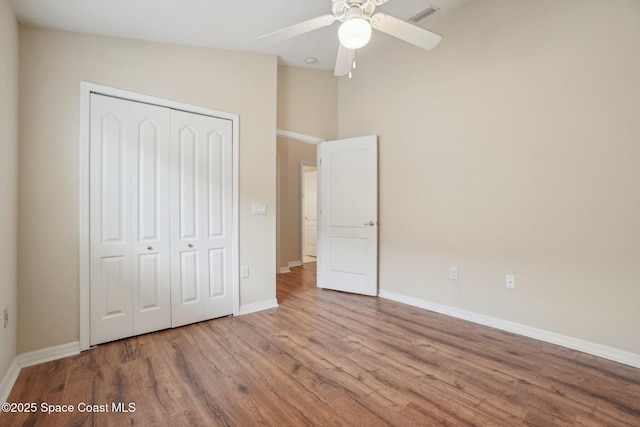 unfurnished bedroom featuring ceiling fan, light hardwood / wood-style floors, vaulted ceiling, and a closet