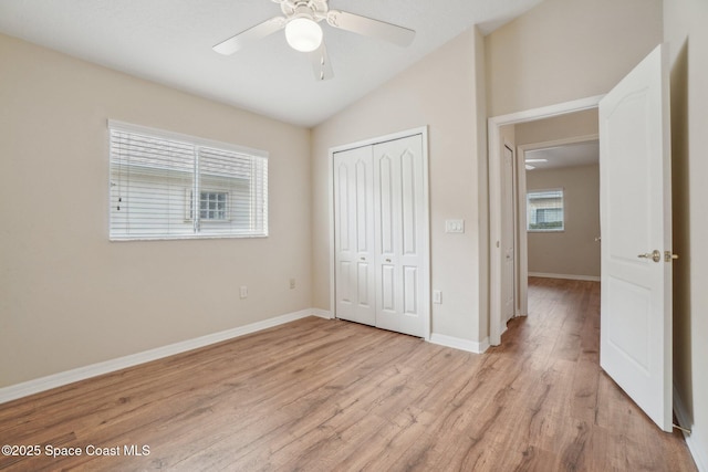 unfurnished bedroom with ceiling fan, a closet, lofted ceiling, and light wood-type flooring