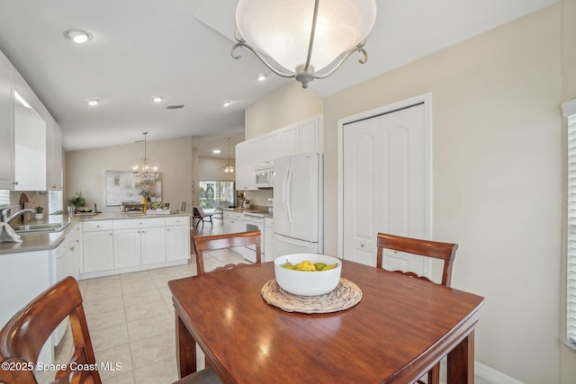 dining area with light tile patterned flooring, lofted ceiling, sink, and a chandelier