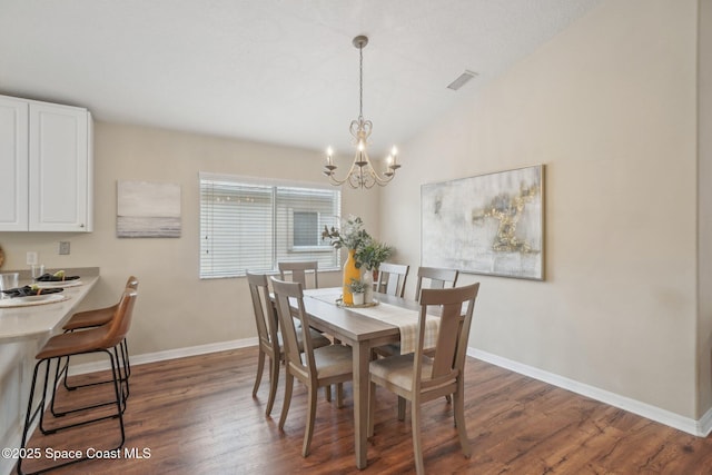 dining room with a chandelier, dark hardwood / wood-style floors, and vaulted ceiling