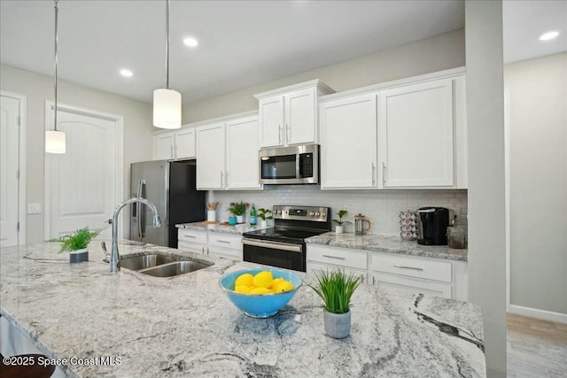 kitchen featuring white cabinets, sink, stainless steel appliances, and hanging light fixtures