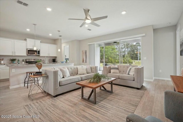 living room with ceiling fan and light hardwood / wood-style floors