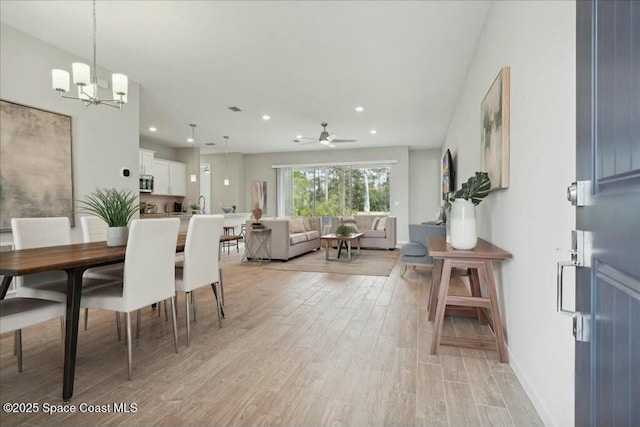 dining space featuring light hardwood / wood-style floors and ceiling fan with notable chandelier