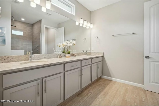 bathroom with hardwood / wood-style flooring, plenty of natural light, tiled shower, and vanity