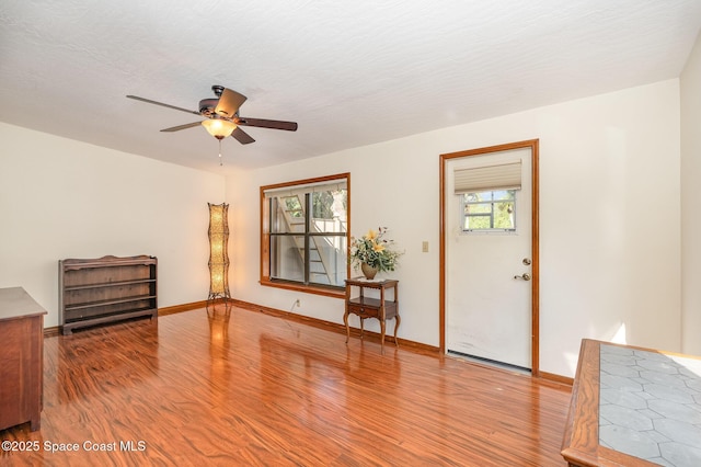 foyer entrance featuring ceiling fan, wood-type flooring, and a textured ceiling