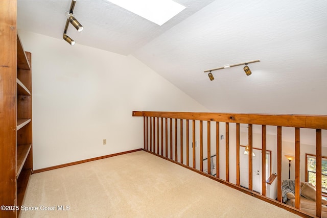 interior space with lofted ceiling with skylight, light colored carpet, and a textured ceiling