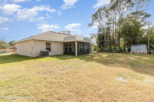 rear view of house featuring a sunroom, cooling unit, a shed, and a lawn