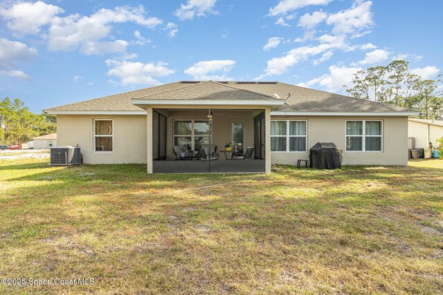 rear view of property with central AC, a sunroom, and a yard