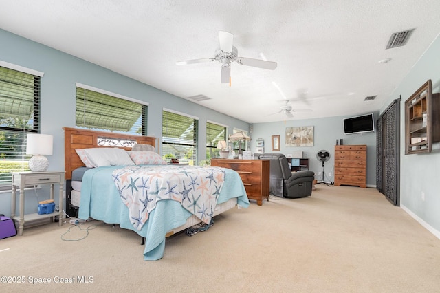 carpeted bedroom with multiple windows, ceiling fan, and a textured ceiling