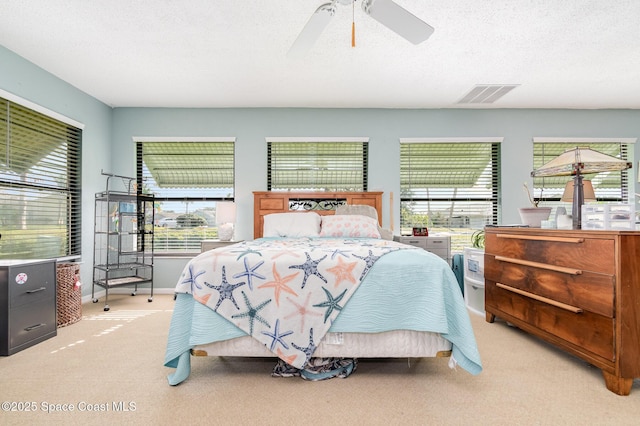 bedroom with a textured ceiling, ceiling fan, and light carpet