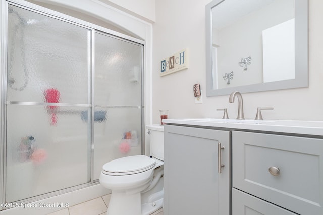 bathroom featuring tile patterned floors, vanity, toilet, and a shower with shower door