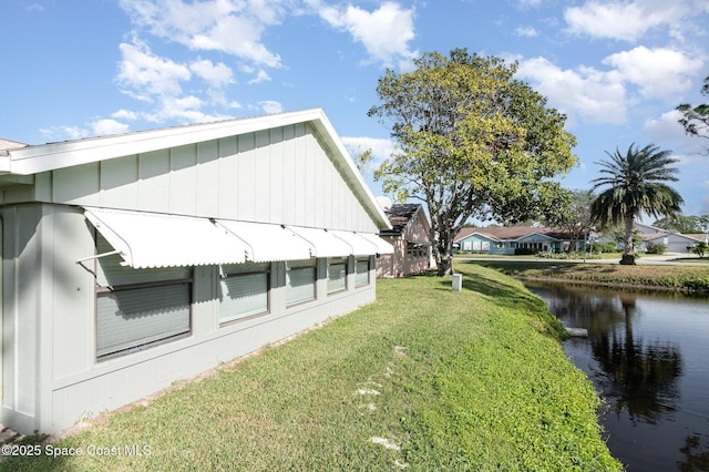 view of side of home featuring a yard and a water view