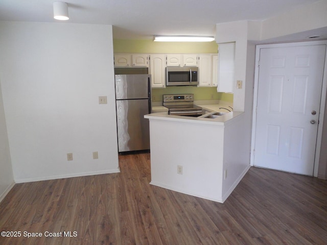 1951 Island Club Dr Unit 37, Indialantic, FL 32903 - kitchen with appliances with stainless steel finishes, dark wood finished floors, light countertops, a sink, and a peninsula