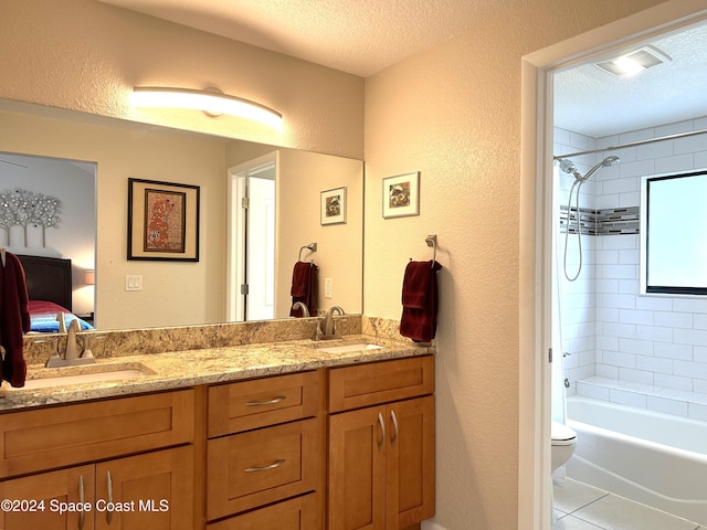 full bathroom with toilet, tiled shower / bath, tile patterned floors, a textured ceiling, and vanity