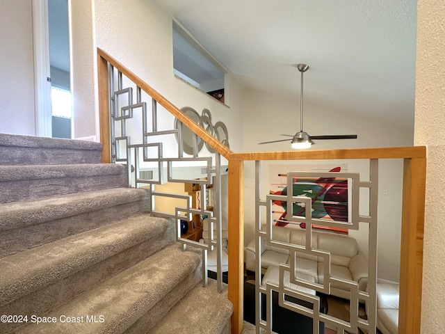 stairway featuring ceiling fan and lofted ceiling