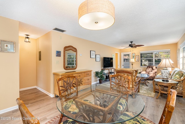 living room featuring ceiling fan, a textured ceiling, and light hardwood / wood-style flooring