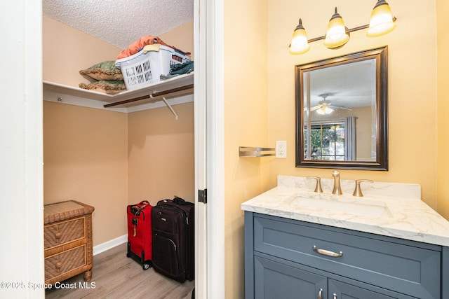 bathroom with hardwood / wood-style flooring, ceiling fan, a textured ceiling, and vanity