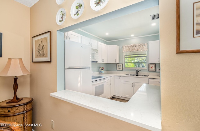 kitchen with kitchen peninsula, sink, white cabinets, and white appliances