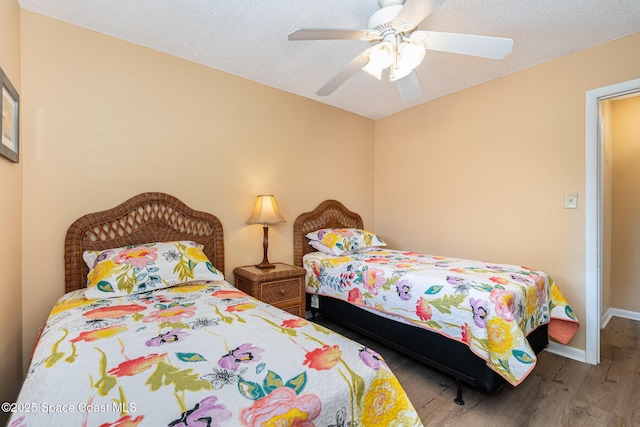 bedroom with ceiling fan, wood-type flooring, and a textured ceiling