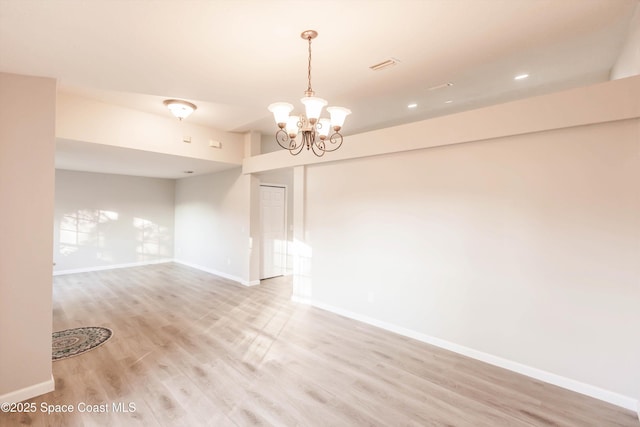 unfurnished room featuring a chandelier and light hardwood / wood-style flooring