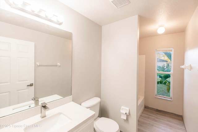 full bathroom with toilet, vanity, wood-type flooring, and a textured ceiling