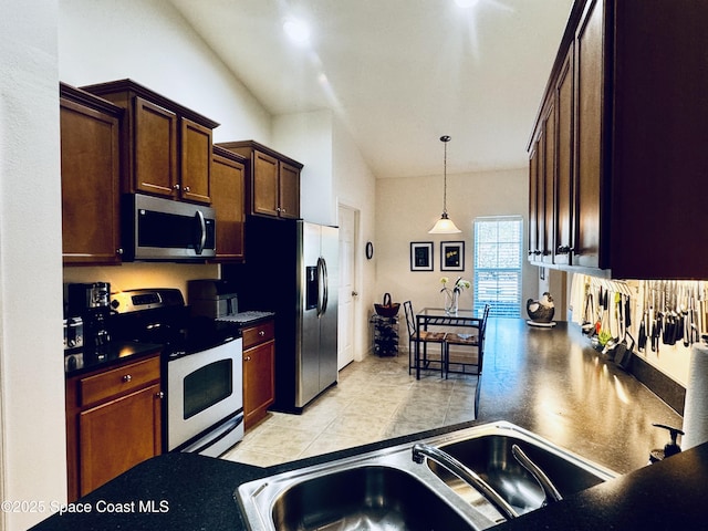 kitchen with appliances with stainless steel finishes, light tile patterned floors, hanging light fixtures, and sink