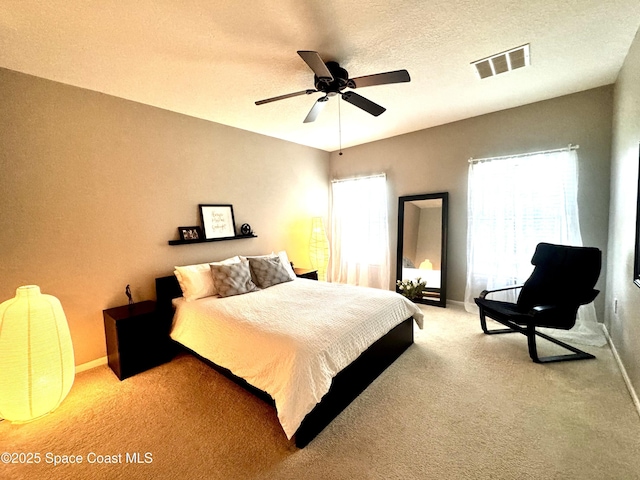 carpeted bedroom featuring ceiling fan and a textured ceiling