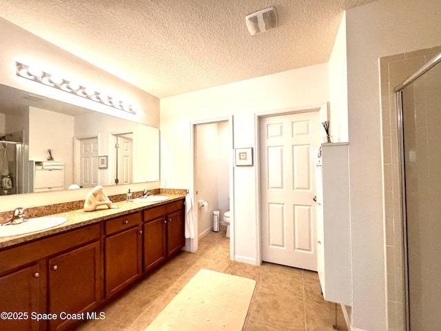 bathroom with a textured ceiling, vanity, an enclosed shower, and toilet