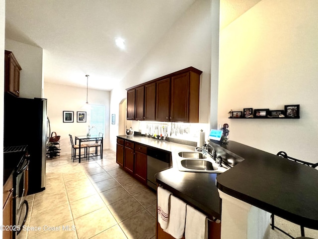 kitchen featuring pendant lighting, lofted ceiling, sink, appliances with stainless steel finishes, and light tile patterned flooring