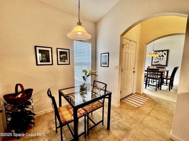 tiled dining room featuring lofted ceiling and an inviting chandelier