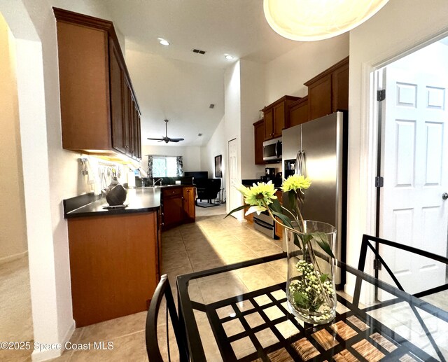 kitchen with kitchen peninsula, appliances with stainless steel finishes, ceiling fan, a high ceiling, and light tile patterned flooring