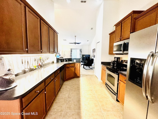 kitchen with kitchen peninsula, ceiling fan, light tile patterned floors, and stainless steel appliances