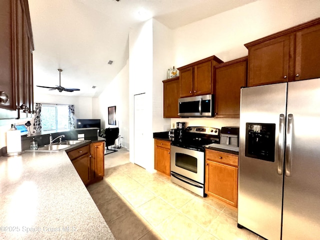 kitchen with appliances with stainless steel finishes, ceiling fan, sink, light tile patterned floors, and high vaulted ceiling