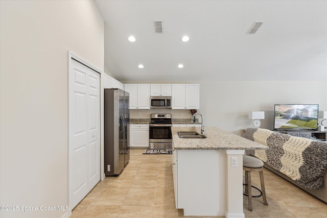 kitchen featuring light stone countertops, a kitchen breakfast bar, stainless steel appliances, sink, and white cabinetry