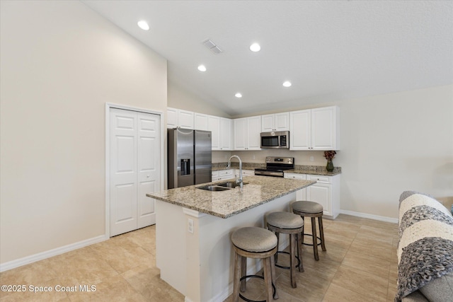 kitchen with appliances with stainless steel finishes, a kitchen breakfast bar, sink, a center island with sink, and white cabinets